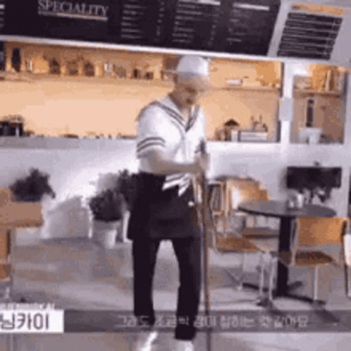 A Man In A Sailor Costume Is Standing In A Restaurant Holding A Sword . GIF
