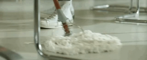 a man in a sailor outfit is standing in front of a counter in a restaurant holding a mop .