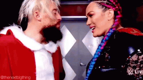 a man in a santa claus outfit is kissing a woman in a pink braid .