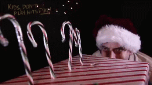 A Man In A Santa Hat Is Looking At Candy Canes GIF