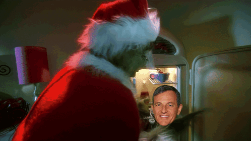 A Man In A Santa Hat Stands In Front Of A Refrigerator GIF