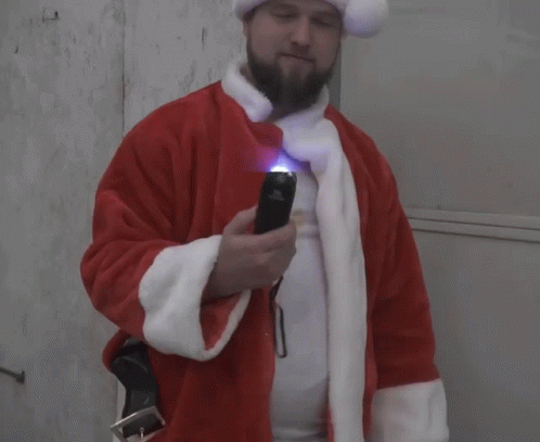 A Man In A Santa Suit Holds A Flashlight GIF