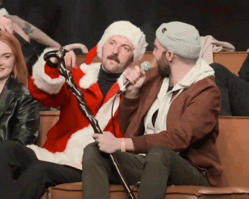 a man in a santa suit is holding a microphone