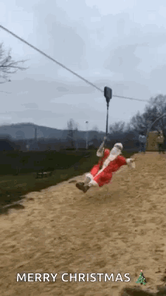 A Man In A Santa Suit Is Riding A Zip Line . GIF