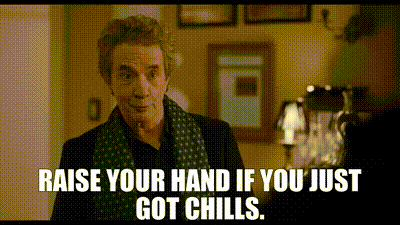 A Man In A Scarf Is Standing In A Room With The Words `` Raise Your Hand If You Just Got Chills '' . GIF