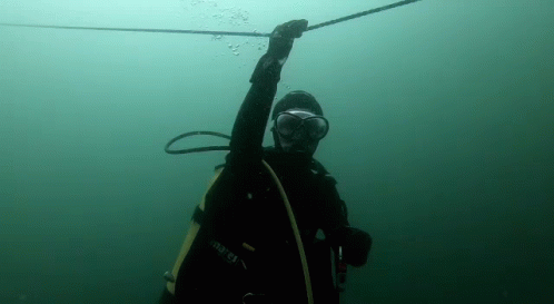 A Man In A Scuba Suit Is Holding A Rope In The Water . GIF