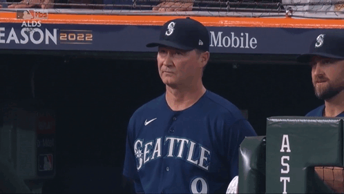 A Man In A Seattle Baseball Uniform Holds A Ticket In His Hand GIF