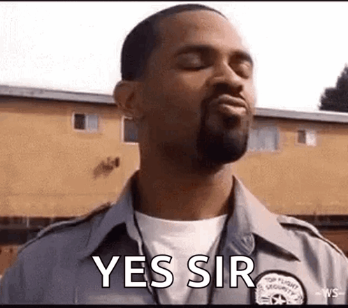 A Man In A Security Uniform Is Standing In Front Of A Building With His Eyes Closed And Saying Yes Sir . GIF