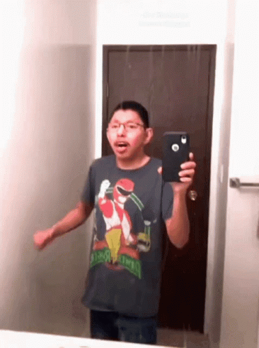 a man in a sesame street shirt is taking a picture of himself in the mirror