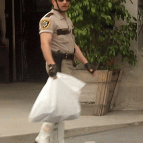 A Man In A Sheriff 'S Uniform Is Holding A Bag GIF