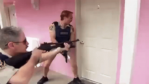 A Man In A Sheriff 'S Uniform Is Pointing A Gun At Another Man In A Room . GIF