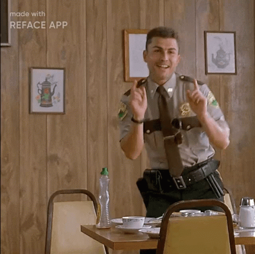 A Man In A Sheriff 'S Uniform Is Sitting At A Table With His Hands In The Air And Says Ah Ha Ha GIF
