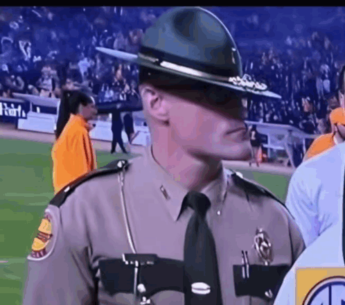 A Man In A Sheriff 'S Uniform Is Standing On A Football Field GIF