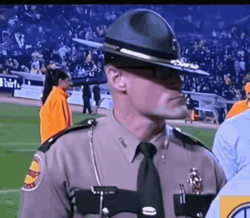 A Man In A Sheriff 'S Uniform Stands On A Stadium Field GIF