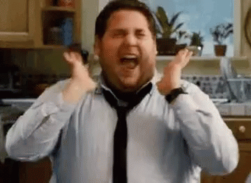 A Man In A Shirt And Tie Is Screaming With His Hands In The Air In A Kitchen . GIF