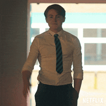 A Man In A Shirt And Tie Is Standing In Front Of A Netflix Sign GIF