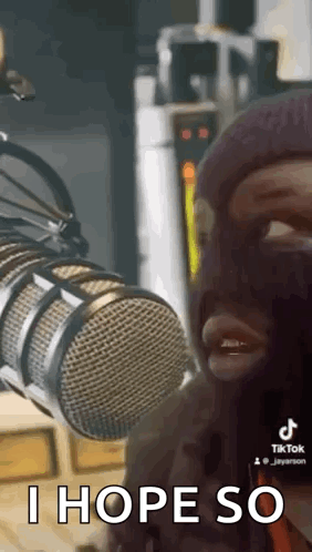 A Man In A Ski Mask Is Standing In Front Of A Microphone . GIF