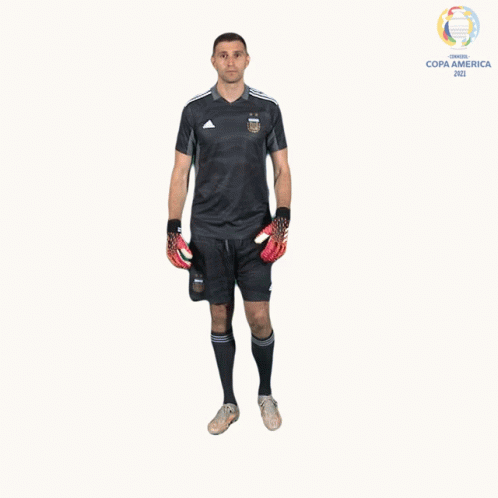 A Man In A Soccer Uniform Is Holding A Pair Of Gloves In Front Of A Copa America Logo GIF