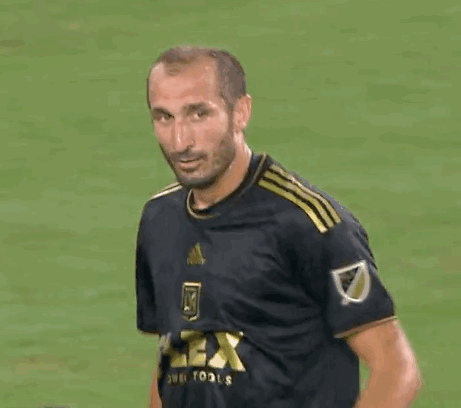 A Man In A Soccer Uniform Is Smiling And Looking At The Camera . GIF