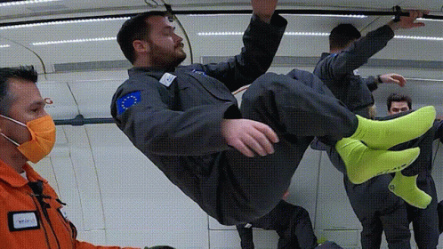A Man In A Space Suit Is Being Lifted In The Air By A Man Wearing A Mask GIF