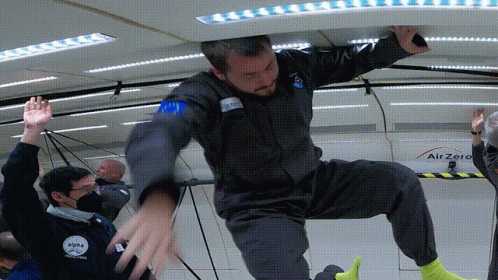 A Man In A Space Suit Is Being Lifted Up By Another Man In A Space Suit GIF