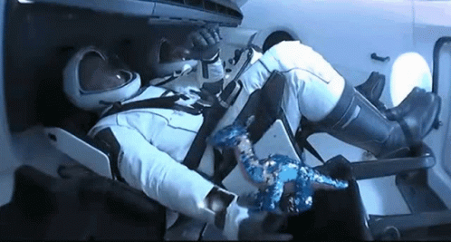 A Man In A Space Suit Is Laying In A Chair With His Feet Up . GIF
