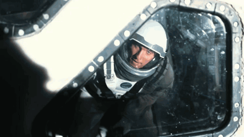 a man in a space suit is looking through a window