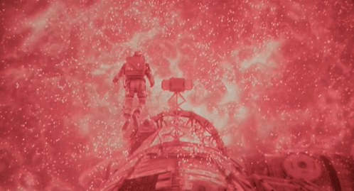 A Man In A Space Suit Is Surrounded By Red Sparkles GIF