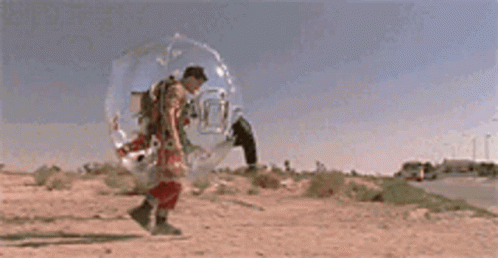 A Man In A Space Suit Is Walking Down A Road GIF