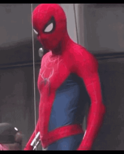 A Man In A Spider Man Costume Is Standing In Front Of A Glass Wall . GIF