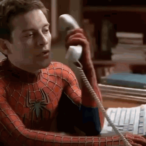 A Man In A Spider-Man Costume Is Talking On A Telephone . GIF