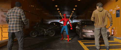 A Man In A Spider Man Costume Stands In A Parking Garage GIF