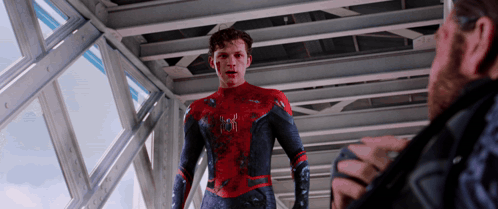 a man in a spider man suit talks to another man in a black jacket