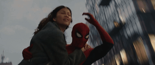A Man In A Spiderman Costume Is Carrying A Woman GIF