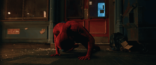A Man In A Spiderman Costume Is Crawling On The Sidewalk GIF