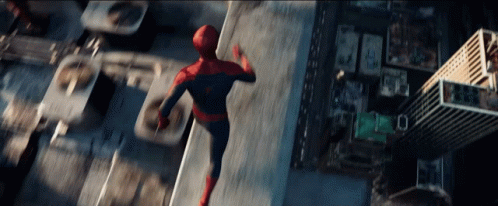 A Man In A Spiderman Costume Is Flying Through The Air Over A City GIF