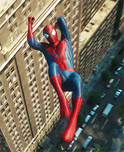 A Man In A Spiderman Costume Is Hanging From The Side Of A Building GIF