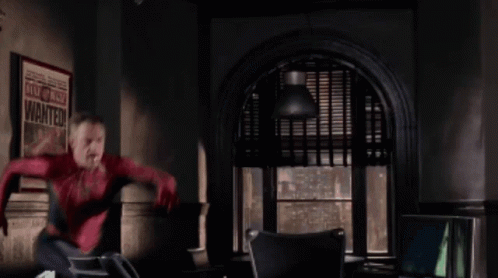 A Man In A Spiderman Costume Is Jumping In Front Of A Poster That Says Wanted GIF