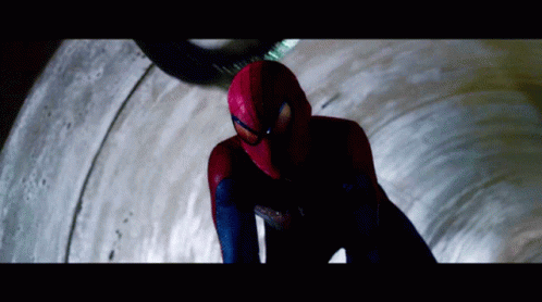 A Man In A Spiderman Costume Is Looking Down At Something GIF