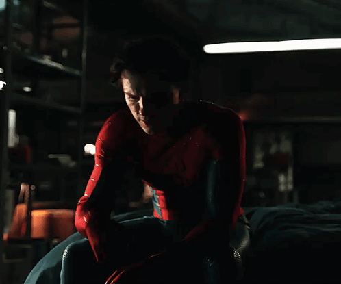 A Man In A Spiderman Costume Is Sitting Down GIF
