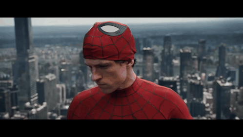 a man in a spiderman costume is standing in front of a city