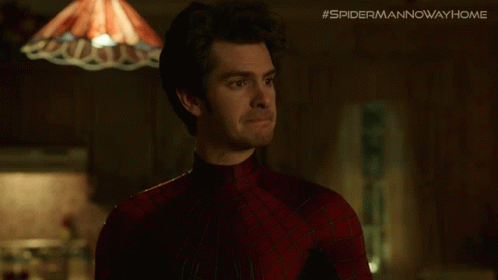A Man In A Spiderman Costume Is Standing In Front Of A Lamp And A Sign That Says #Spidermannowwayhome GIF