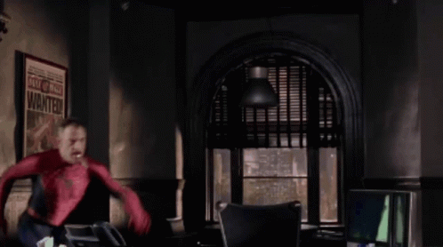 A Man In A Spiderman Costume Is Standing In Front Of A Poster That Says Wanted GIF