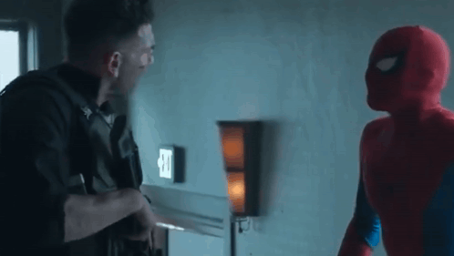 A Man In A Spiderman Costume Is Standing Next To A Man In A Punisher Costume In A Room . GIF