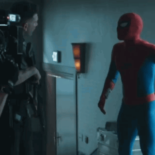 A Man In A Spiderman Costume Is Talking To Another Man GIF