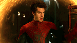 A Man In A Spiderman Costume Stands In Front Of A Fire GIF