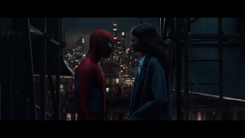 A Man In A Spiderman Costume Stands Next To A Woman In A Suit GIF