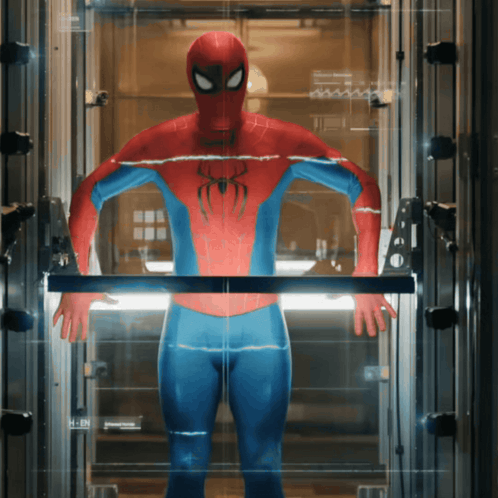 A Man In A Spiderman Suit Is Standing In A Glass Elevator GIF