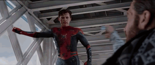 a man in a spiderman suit is standing next to a man in a black shirt .