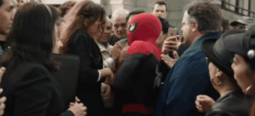 a man in a spiderman suit is surrounded by people